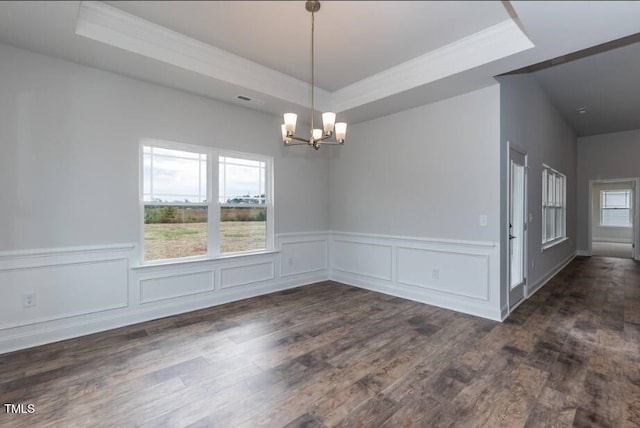 empty room with a tray ceiling, a chandelier, crown molding, dark wood finished floors, and plenty of natural light