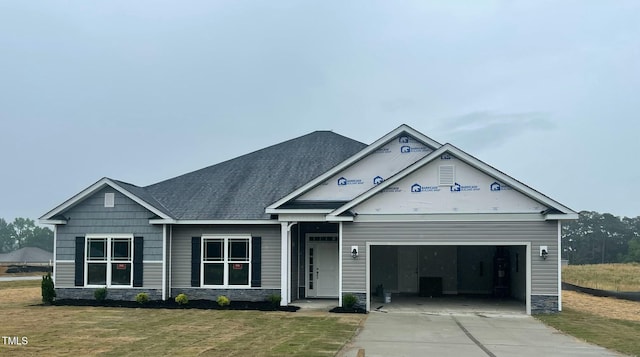 view of front of property with stone siding, driveway, a front lawn, and an attached garage