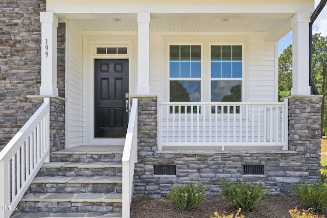 doorway to property featuring covered porch and stone siding
