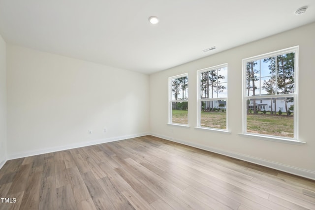 spare room with healthy amount of natural light, baseboards, and light wood-style floors
