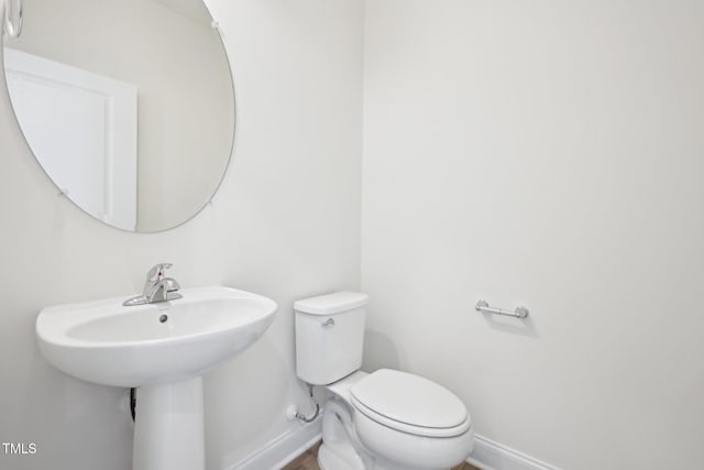 bathroom featuring baseboards, toilet, and a sink
