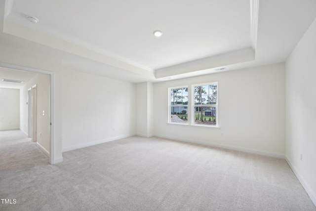 carpeted spare room with a tray ceiling, crown molding, and baseboards
