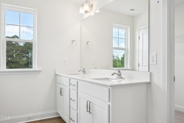full bath with baseboards and double vanity