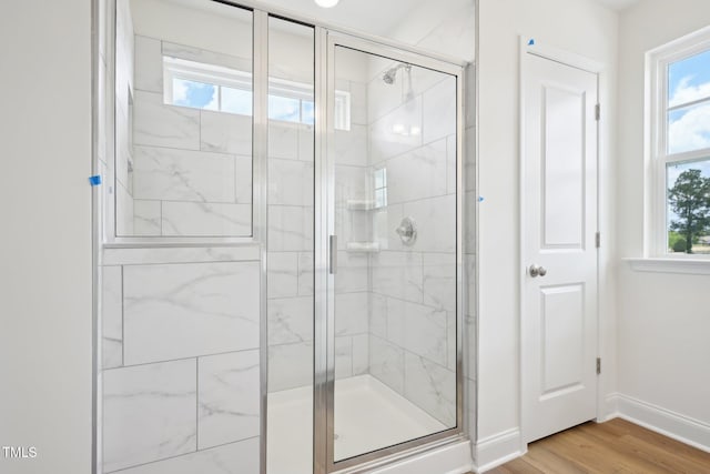 full bathroom featuring healthy amount of natural light, a stall shower, and baseboards