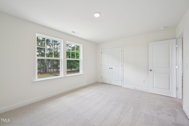 unfurnished bedroom featuring light carpet, baseboards, and a closet