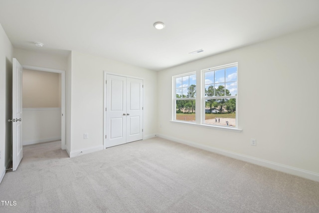 unfurnished bedroom featuring light colored carpet, baseboards, and a closet