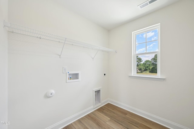 clothes washing area with hookup for an electric dryer, wood finished floors, baseboards, washer hookup, and gas dryer hookup