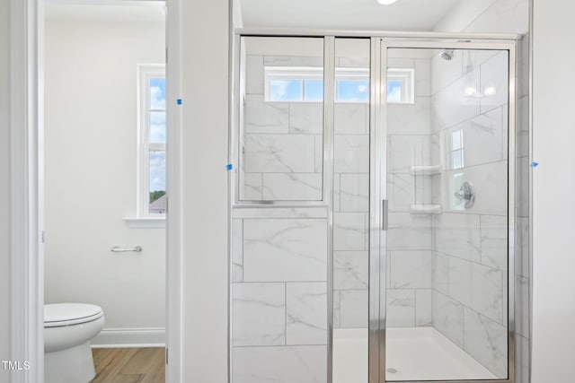 full bath featuring toilet, a shower stall, baseboards, and wood finished floors