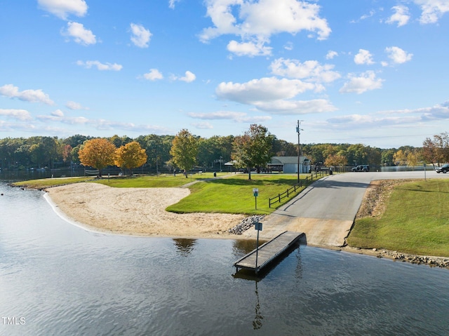 exterior space featuring a water view, a lawn, and a dock