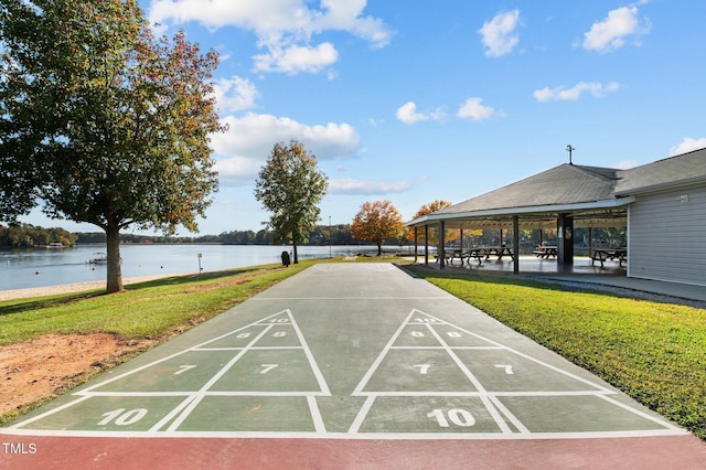 view of community with a water view, shuffleboard, and a lawn