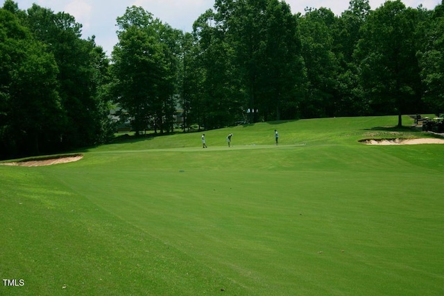 view of community featuring view of golf course and a yard