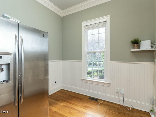 kitchen featuring visible vents, stainless steel fridge, ornamental molding, wainscoting, and wood finished floors