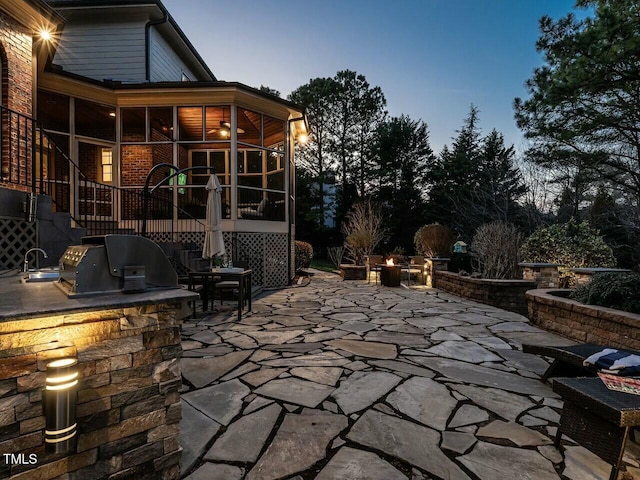 view of patio featuring a sink, a sunroom, and area for grilling