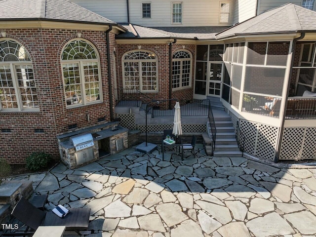exterior space featuring a sunroom and an outdoor kitchen