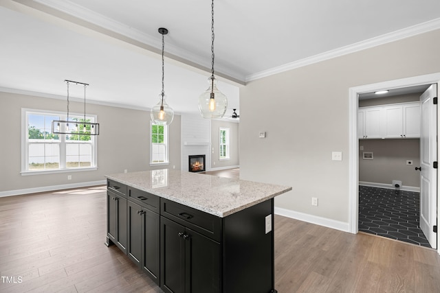 4924 Zebulon Rd, Zebulon, NC 27597 - kitchen featuring dark cabinetry, wood finished floors, ornamental molding, a glass covered fireplace, and open floor plan