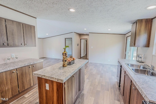 1326 Stephens Dr, Roxboro, NC 27573 - kitchen featuring a sink, light wood finished floors, light countertops, brown cabinetry, and a kitchen island