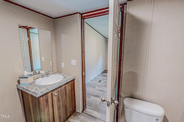 1326 Stephens Dr, Roxboro, NC 27573 - half bathroom with vanity, wood finished floors, toilet, and ornamental molding
