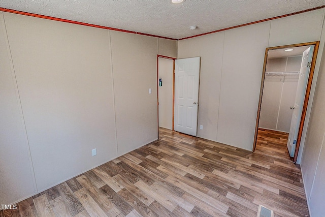 1326 Stephens Dr, Roxboro, NC 27573 - unfurnished bedroom with wood finished floors, crown molding, a textured ceiling, a walk in closet, and a closet