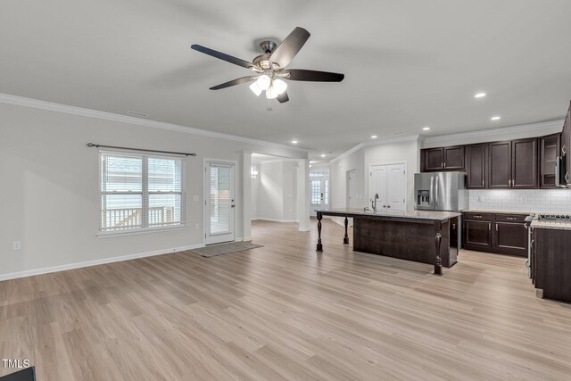 233 Stone River Dr, Wendell, NC 27591 - kitchen with decorative backsplash, light wood-style flooring, ceiling fan, dark brown cabinets, and a kitchen island