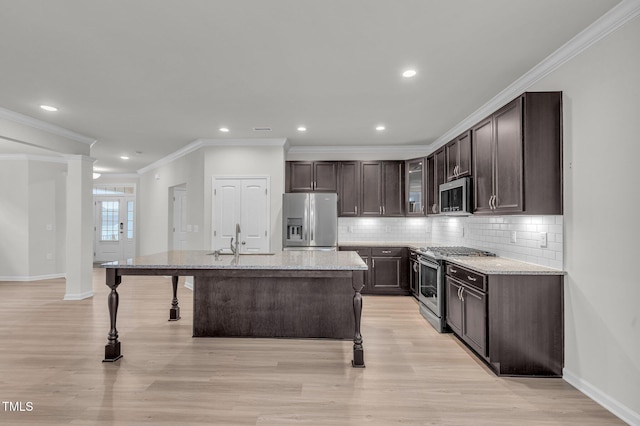 233 Stone River Dr, Wendell, NC 27591 - kitchen featuring backsplash, appliances with stainless steel finishes, a center island with sink, light wood-style floors, and dark brown cabinets