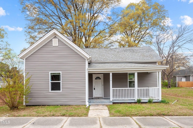 view of front of house featuring a porch, roof with shingles, and a front yard