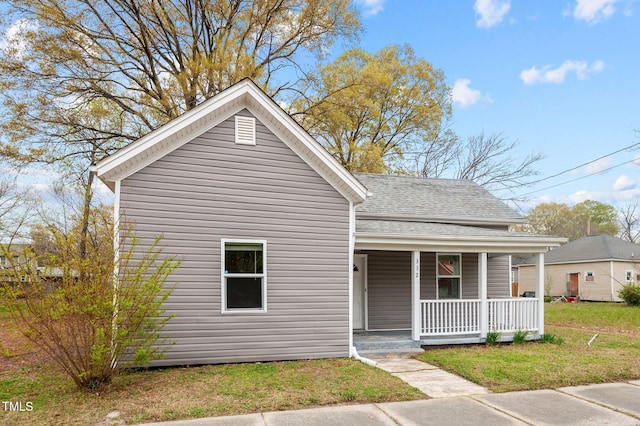 view of front of house with roof with shingles, a porch, and a front yard