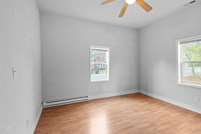 unfurnished room featuring baseboard heating, a ceiling fan, visible vents, and a wealth of natural light