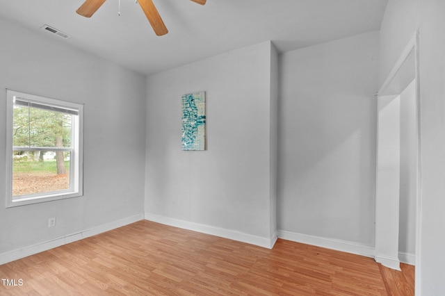 unfurnished room featuring light wood finished floors, visible vents, baseboards, and a ceiling fan
