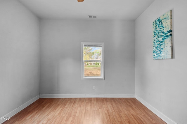 unfurnished room featuring light wood finished floors, visible vents, and baseboards