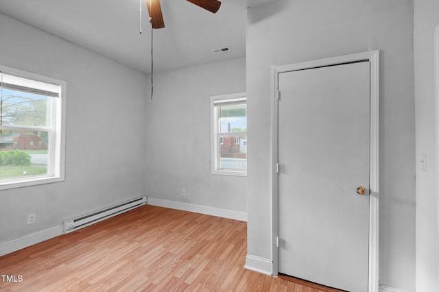 unfurnished room featuring visible vents, baseboards, a baseboard radiator, light wood-type flooring, and a ceiling fan