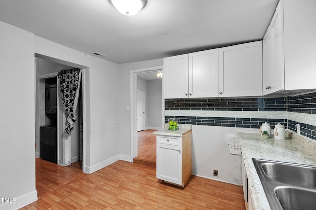 kitchen featuring white cabinets, light wood-style floors, baseboards, and backsplash
