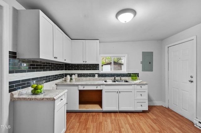 kitchen featuring a sink, light countertops, light wood finished floors, and electric panel
