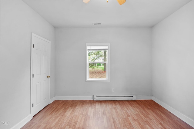 spare room featuring a baseboard radiator, light wood finished floors, baseboards, and a ceiling fan