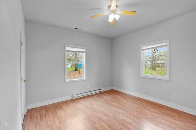 unfurnished room featuring light wood finished floors, baseboard heating, baseboards, and visible vents
