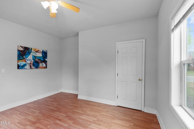 spare room with light wood-style floors, ceiling fan, and baseboards