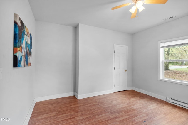 empty room with visible vents, baseboards, ceiling fan, baseboard heating, and light wood finished floors