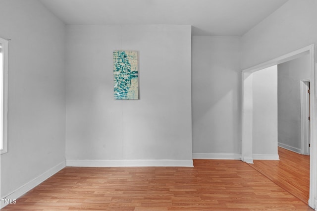 spare room featuring light wood-style floors and baseboards