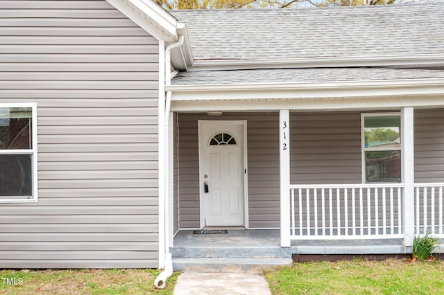 doorway to property featuring a shingled roof and covered porch