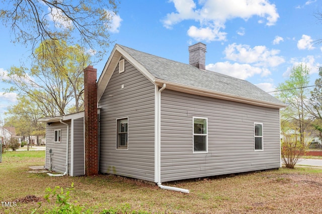 view of home's exterior featuring a yard, a chimney, and a shingled roof