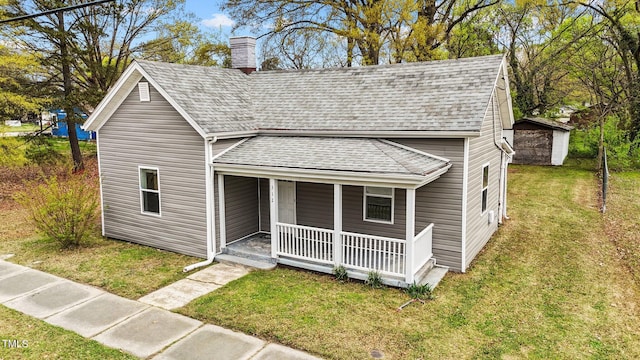 view of front of property featuring roof with shingles, a porch, a chimney, and a front yard