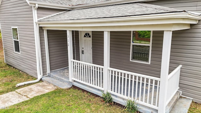 view of exterior entry featuring a porch and a shingled roof