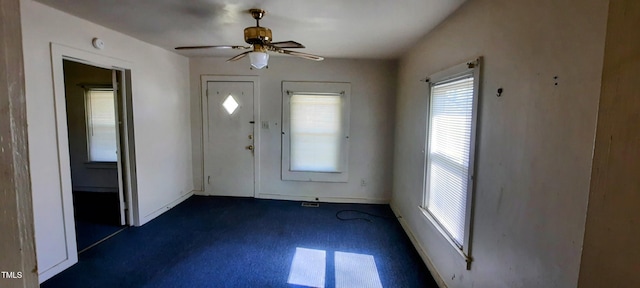 entryway featuring dark carpet, baseboards, and a ceiling fan