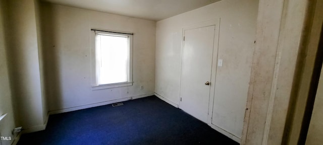 unfurnished bedroom with dark carpet, baseboards, and visible vents
