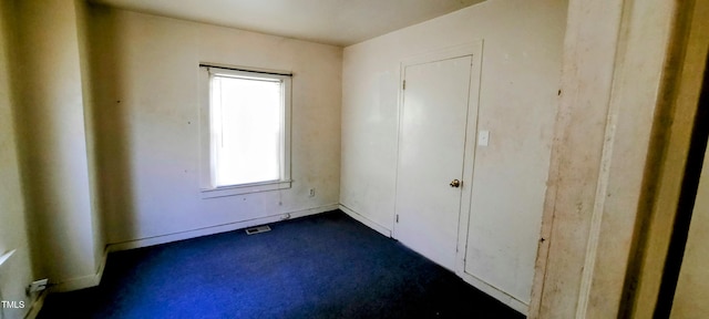 unfurnished bedroom with visible vents and dark colored carpet