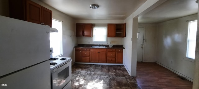 kitchen with range hood, a sink, dark countertops, white appliances, and brown cabinets