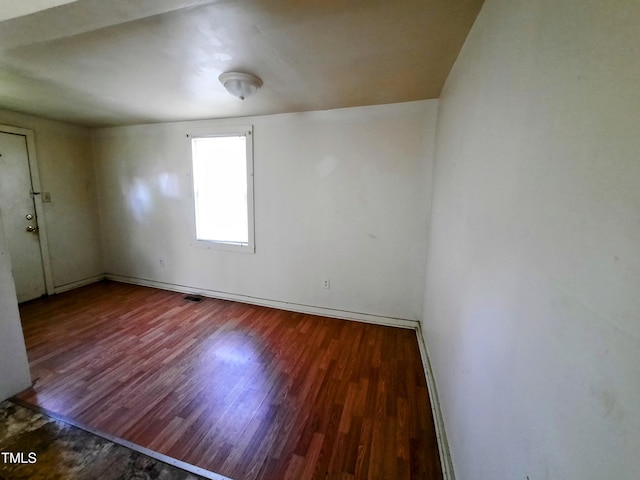 empty room with wood finished floors, baseboards, and visible vents