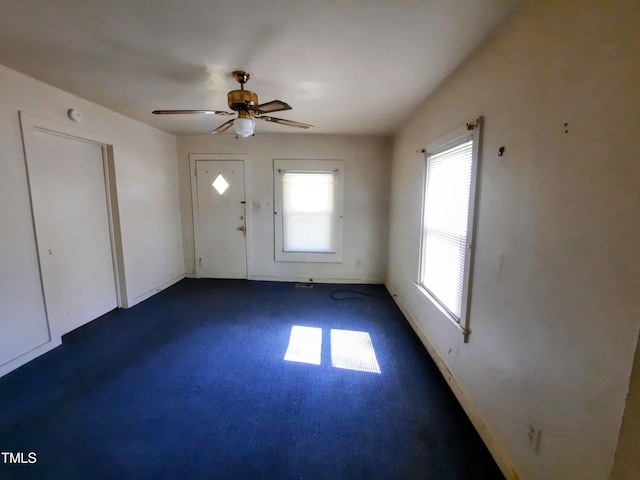 entrance foyer featuring dark colored carpet and a ceiling fan