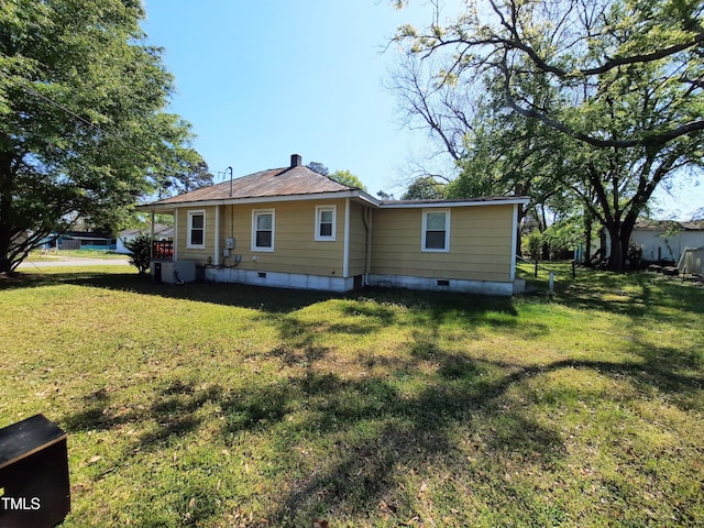 back of house featuring a lawn and crawl space