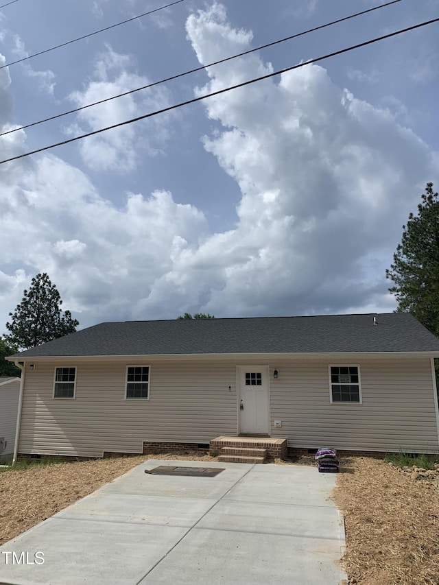 back of property featuring a shingled roof, a patio area, and crawl space