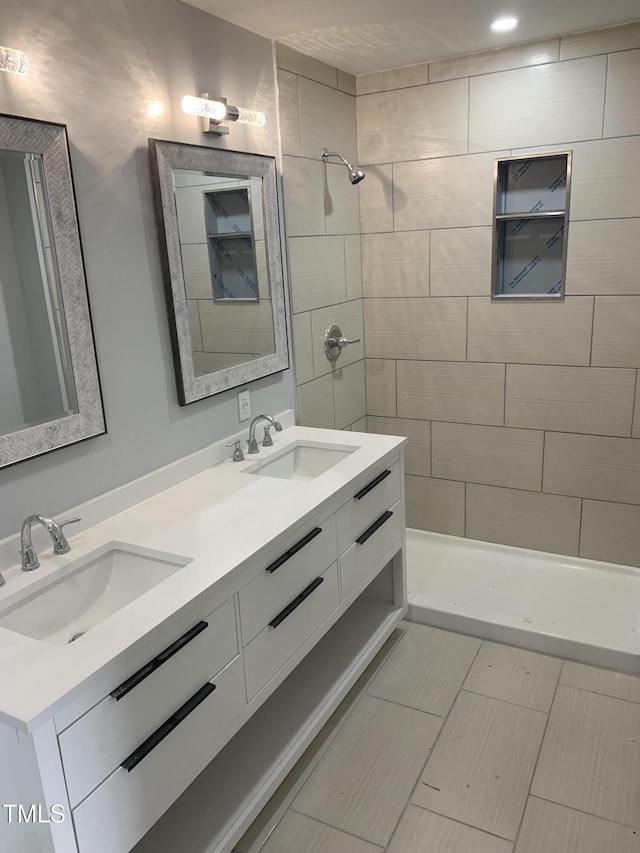 full bath with double vanity, tiled shower, and a sink